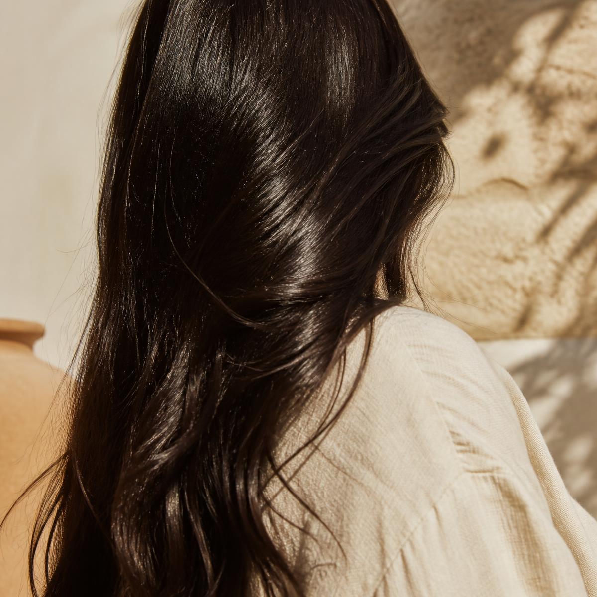 Close-up of glossy dark hair catching warm light